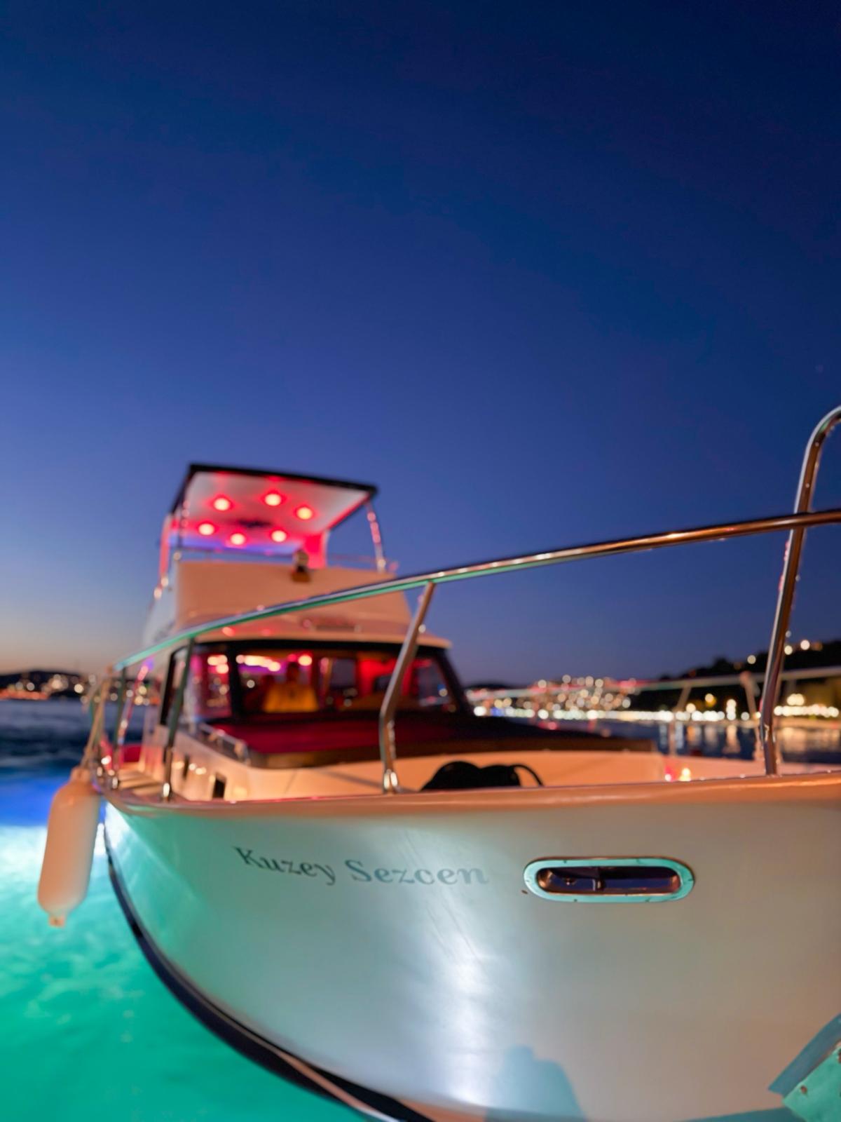 luxury yacht cruising on the bosphorus at night with the istanbul bridge illuminated in golden lights against a deep navy sky